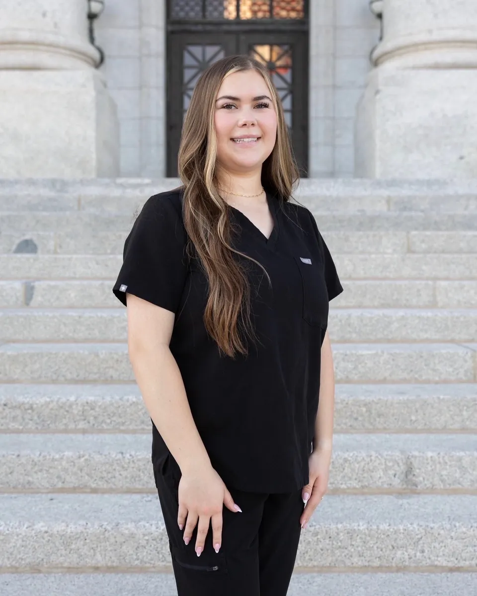 Macey, owner of Almond & Honey Nail Co., smiling on stone steps